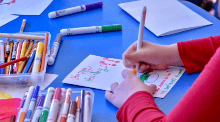 a child making christmas cards with paper and washable markers
