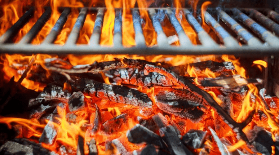 burning briquettes and wood chunks inside a charcoal grill closeup