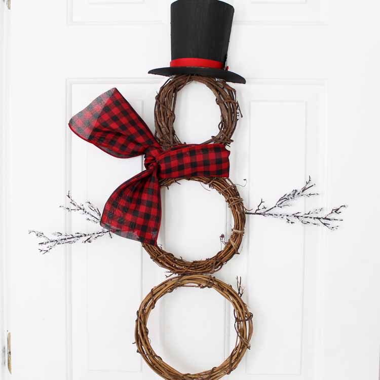 A DIY snowman wreath made from grapevine wreaths, holly leaves, and paper mache.