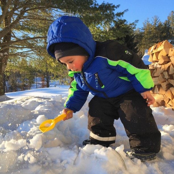 kid shoveling snow with snow toy shovel in winter
