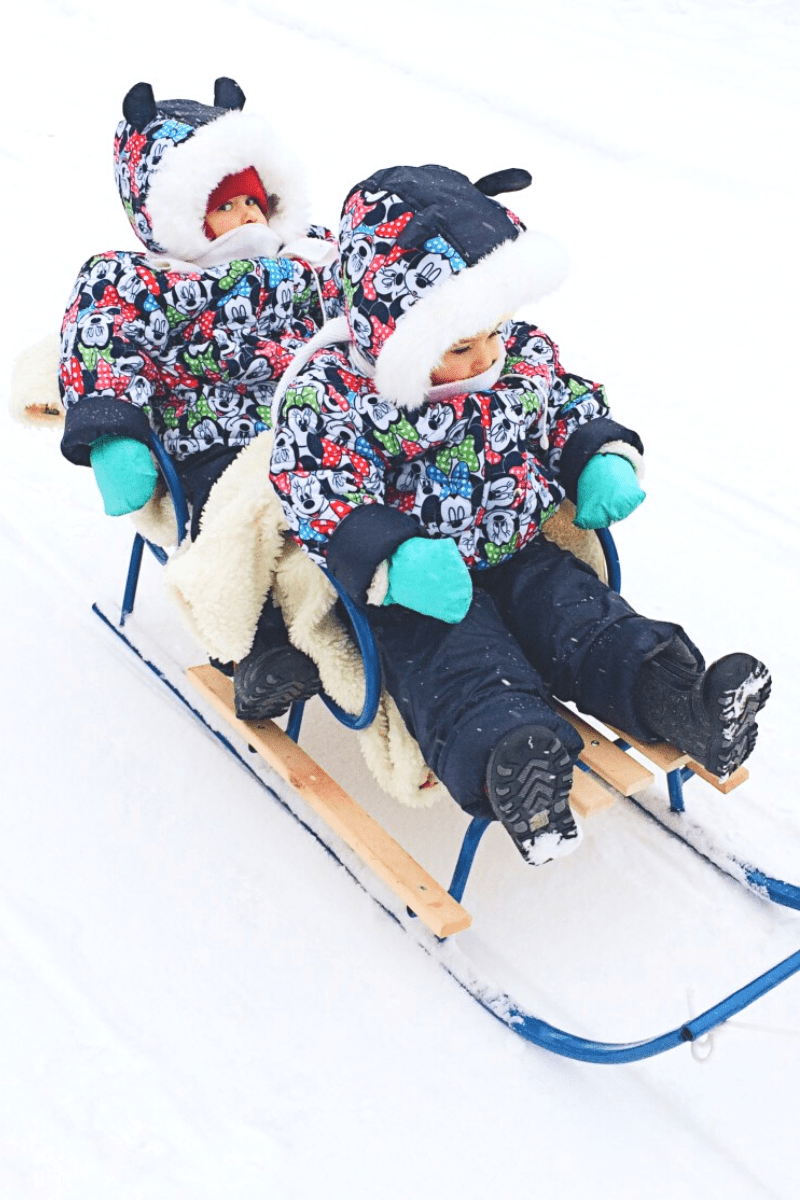 twin kids sledding on wooden steel runner sled
