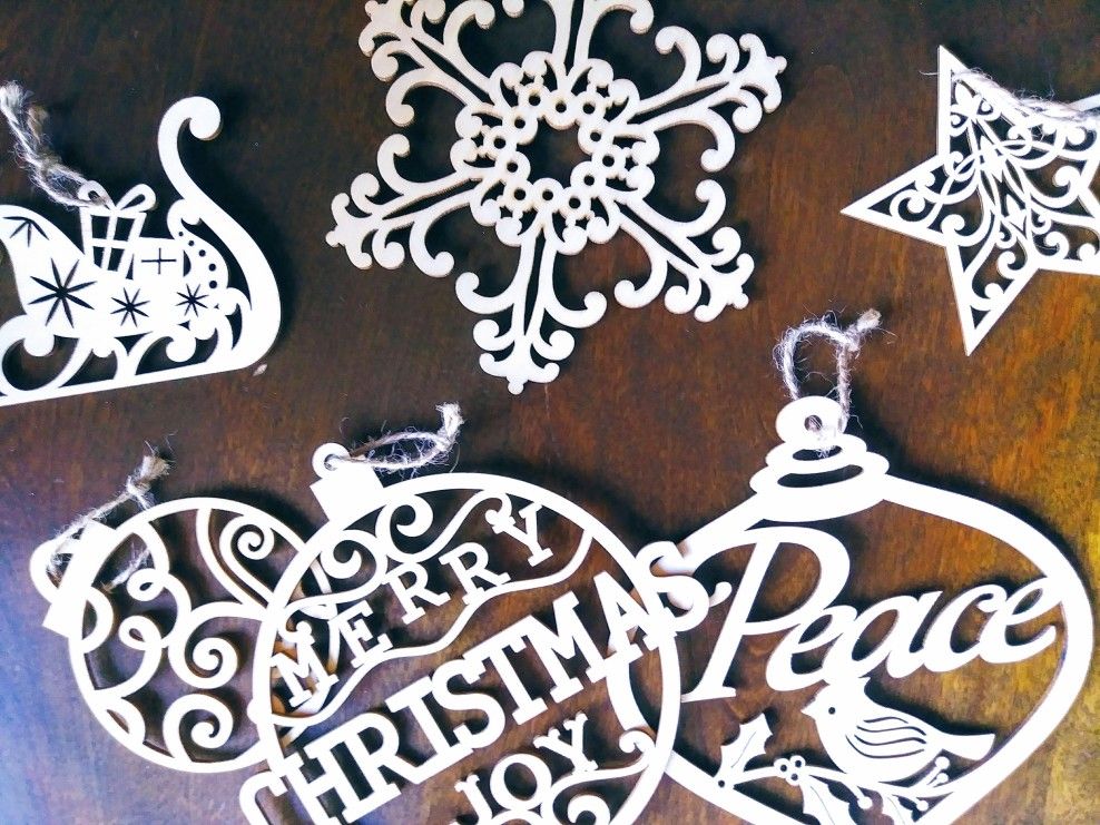 A flatlay of wooden cutout Christmas tree ornaments on wood chair.