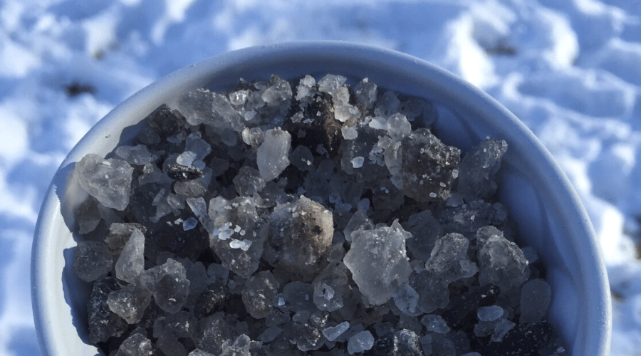 gray rock salt in a bowl outdoors in snow