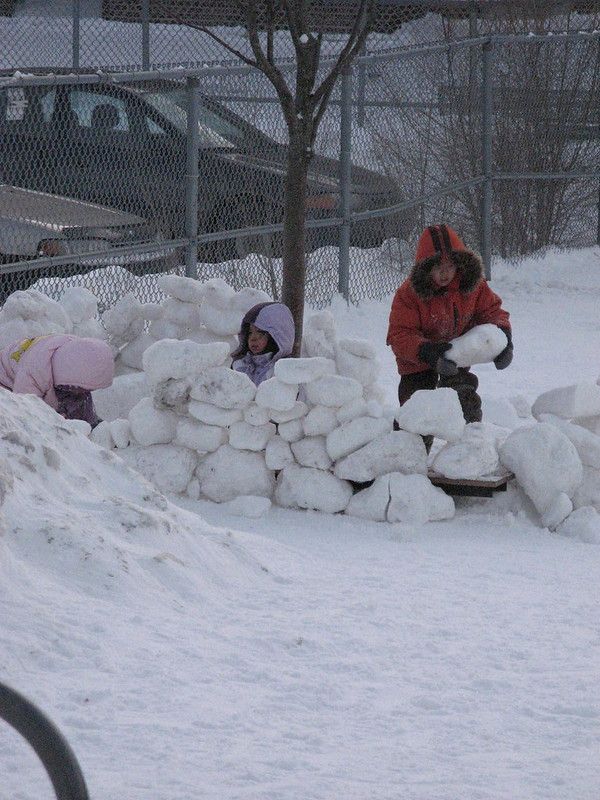 kids using hard blocks of snow to build a fort