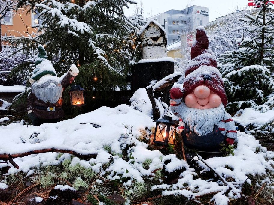 christmas gnome in red hat outdoors in snow carrying lantern