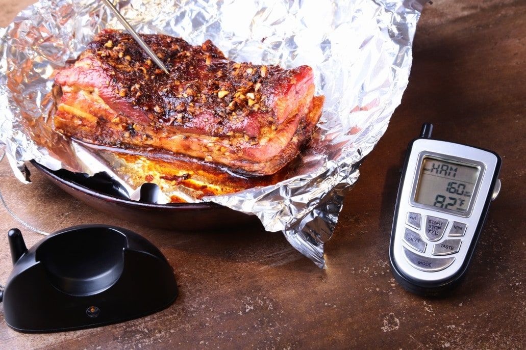 Grilled Steak in a pan and Wireless Remote Digital Cooking Food Probe Meat Thermometer For Grill on a black background. Copy space.