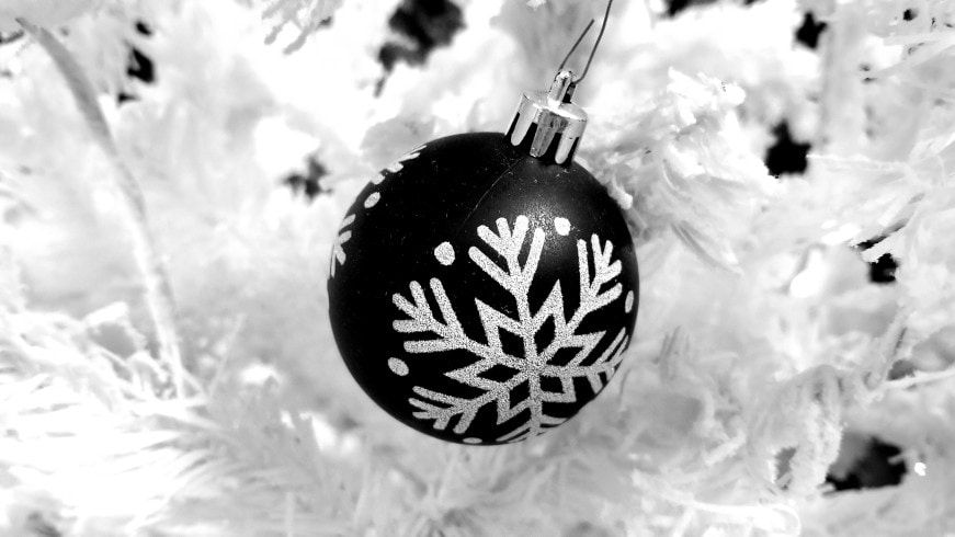matte black ornament with a sparkly white snowflake on a solid white Christmas tree. Modern Christmas tree