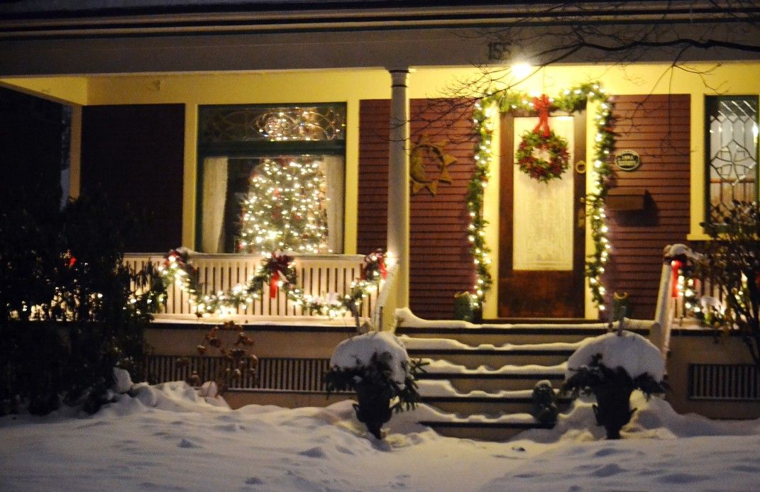 front porch with christmas lights and garland in snow