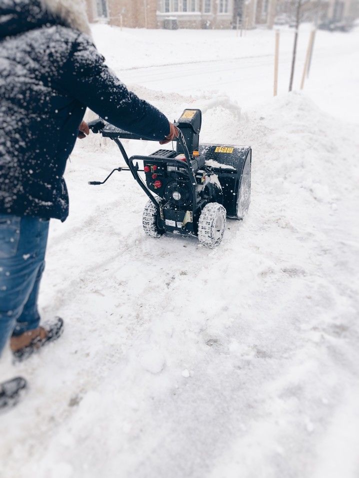 Canadian winter. Man is clearing snow from a driveway with a snowblower