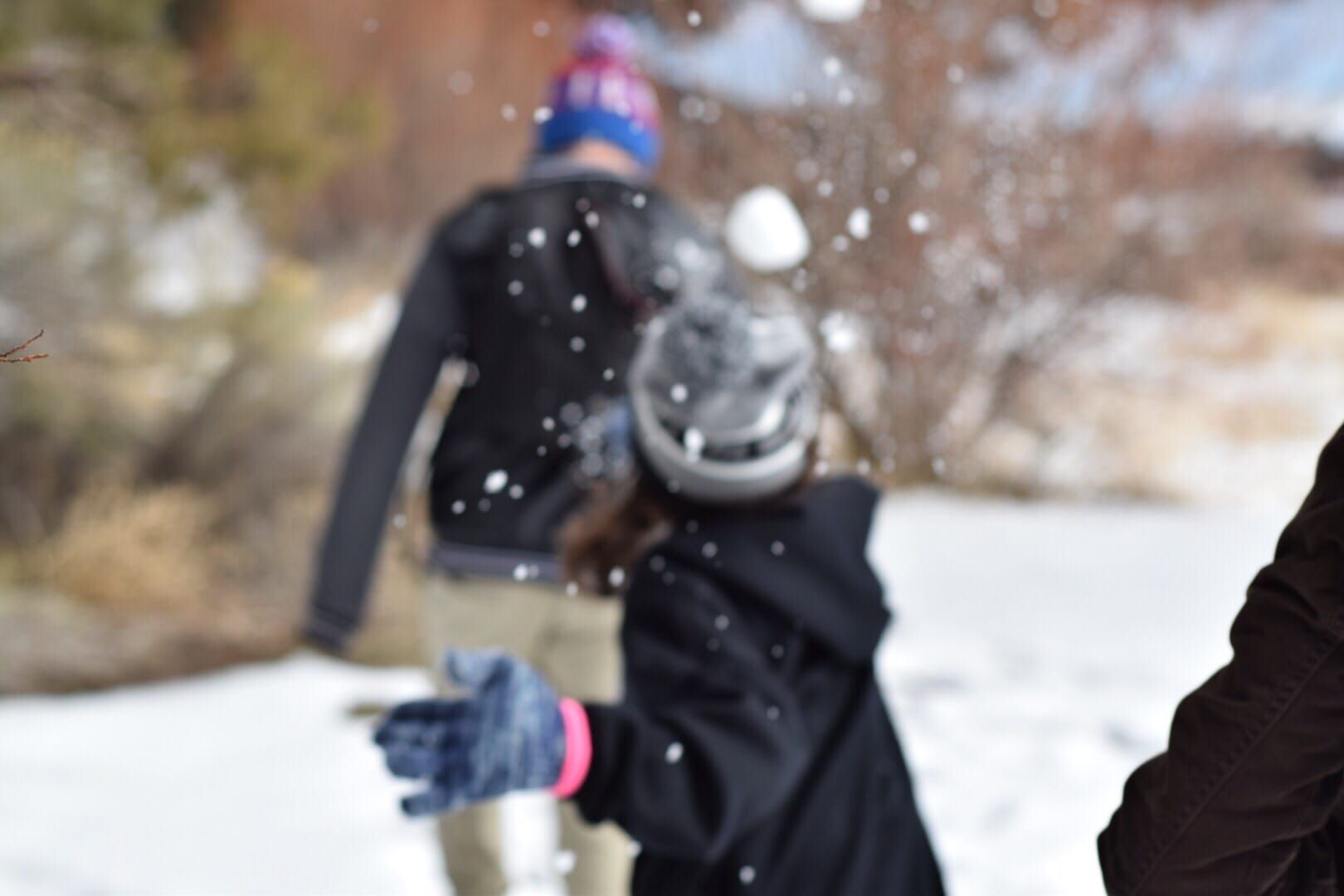 girl throwing snowball at boy outdfoors winter snowball fight maker