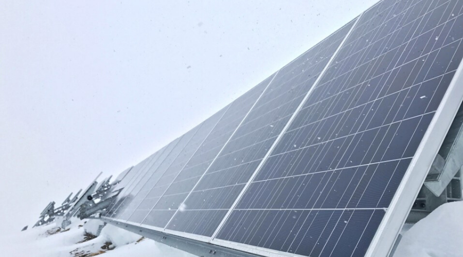 a long line of solar panels with snow falling on them