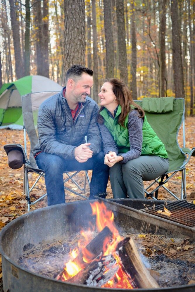 couple sitting beside a campfire in pine forest pine firewood outdoor use