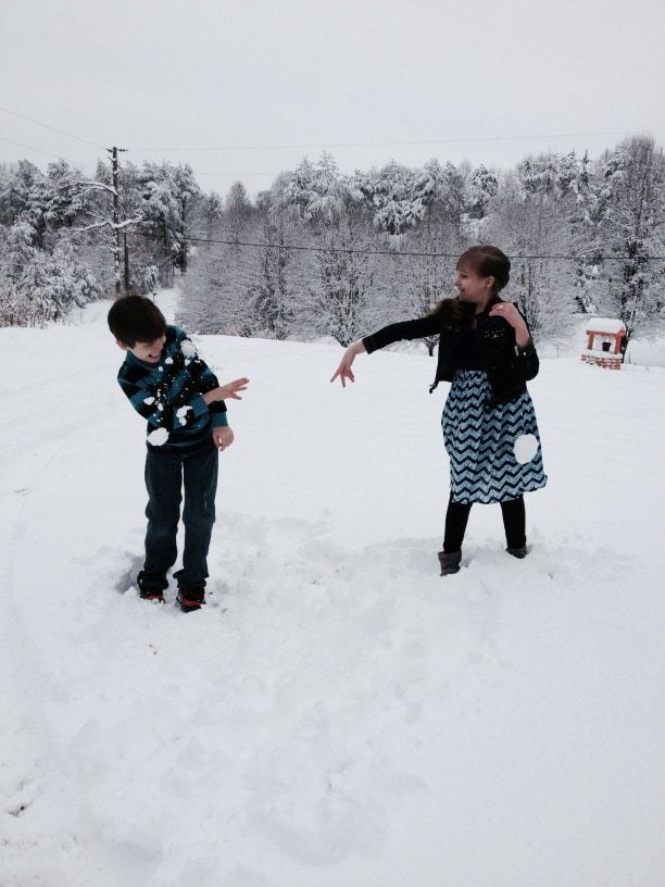 kids throwing snowballs at one another in backyard outdoors winter