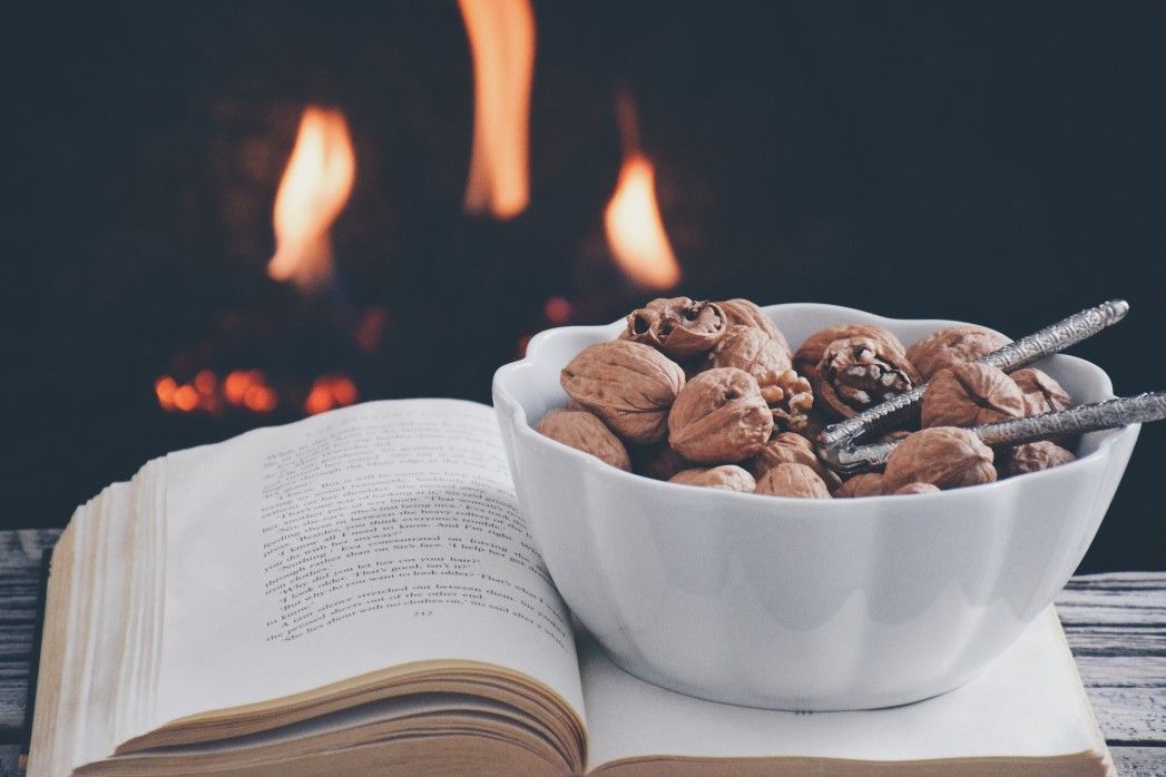 bowl of walnuts on open book with firewood fire in background