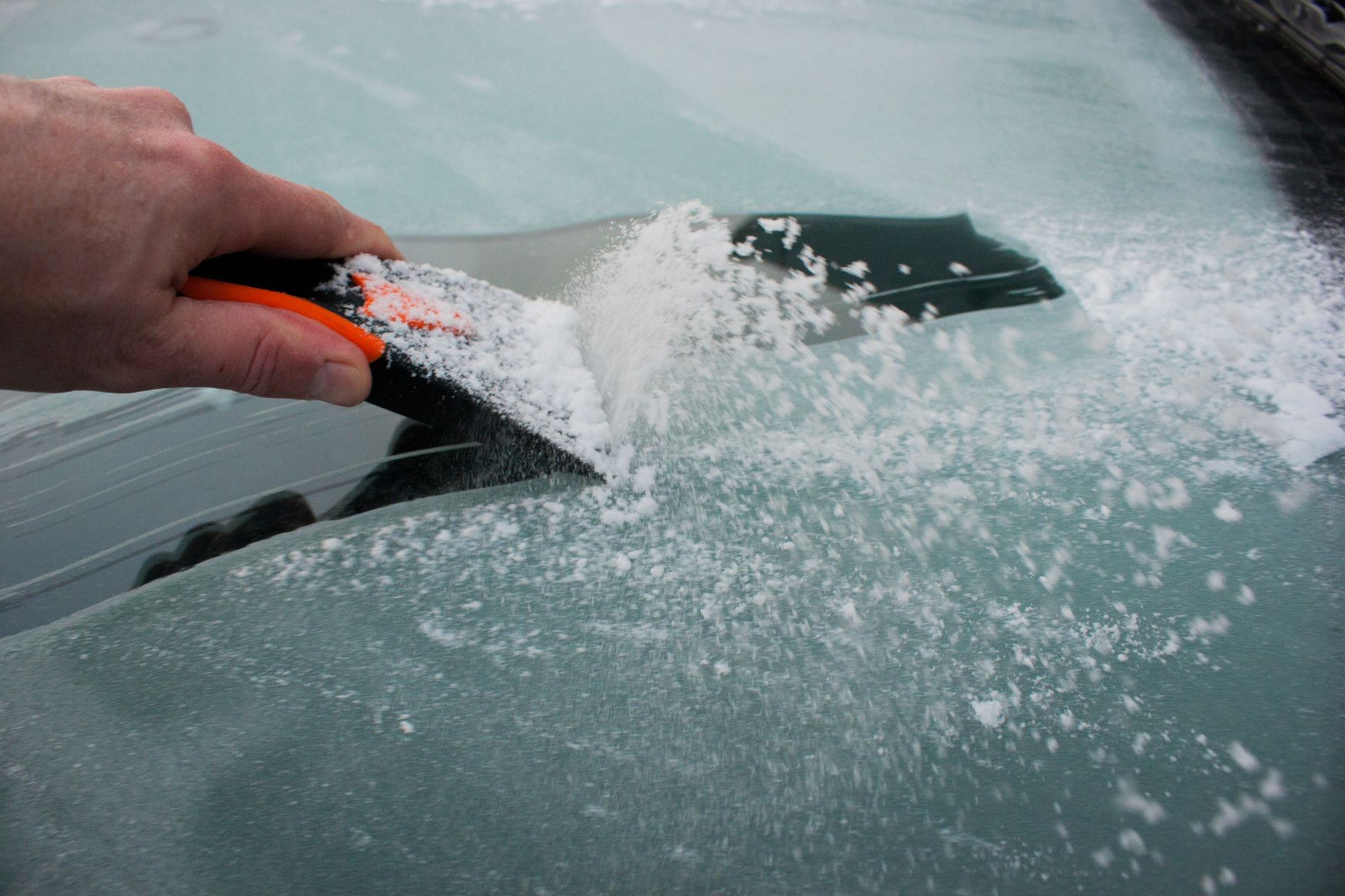 traditional ice scraper in use closeup on windshield