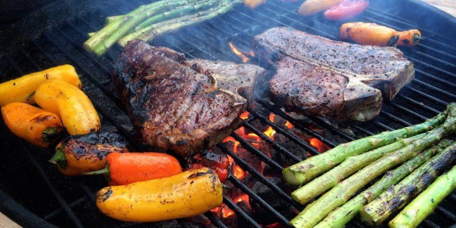Charcoal grill with sizzling steaks and veggies.