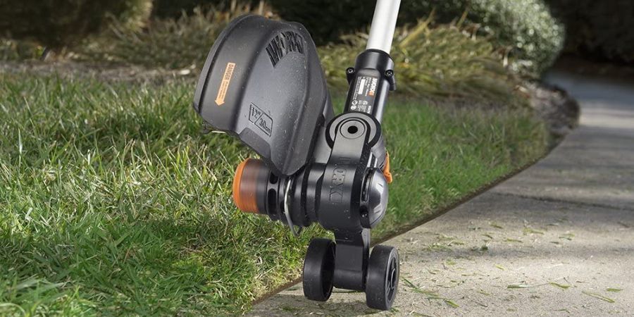 Cordless string trimmer doubling as an edger, cutting the edge of a lawn.