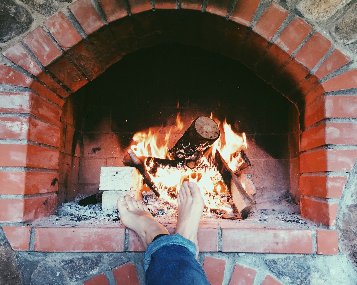 woodburning fireplace indoors with feet resting on brick
