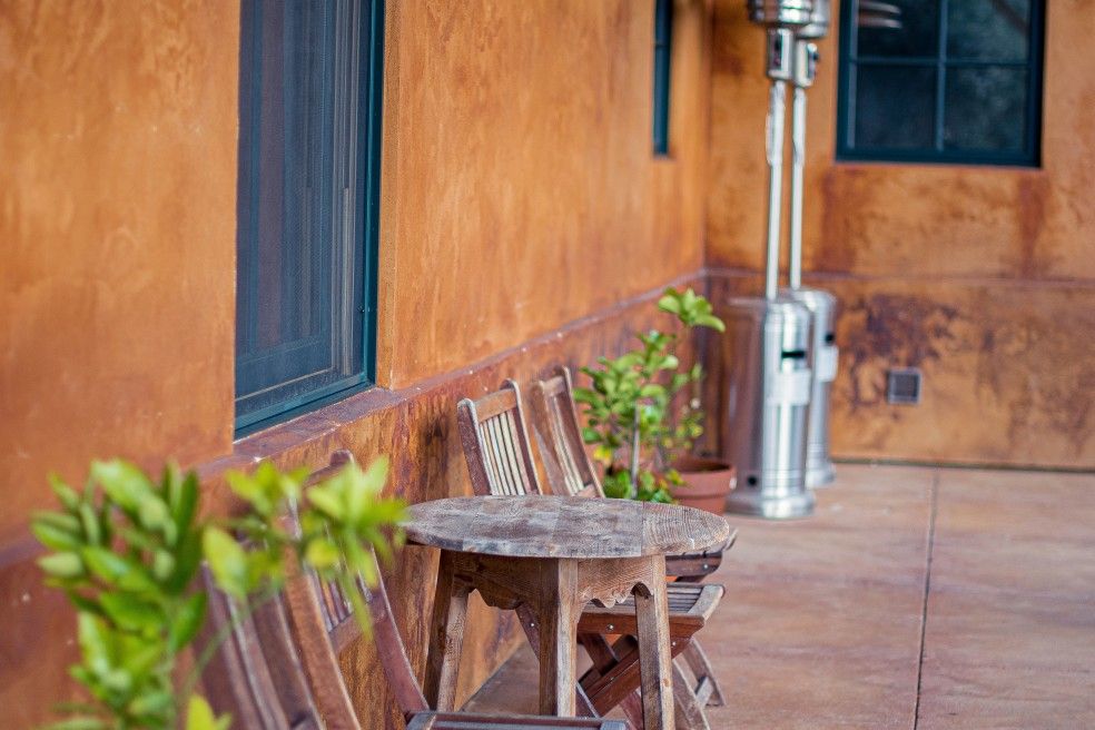 patio heaters Rustic wooden outdoor chairs and a table against orange wall