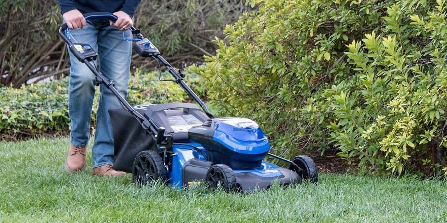 Man pushing a blue Kobalt lawn mower.