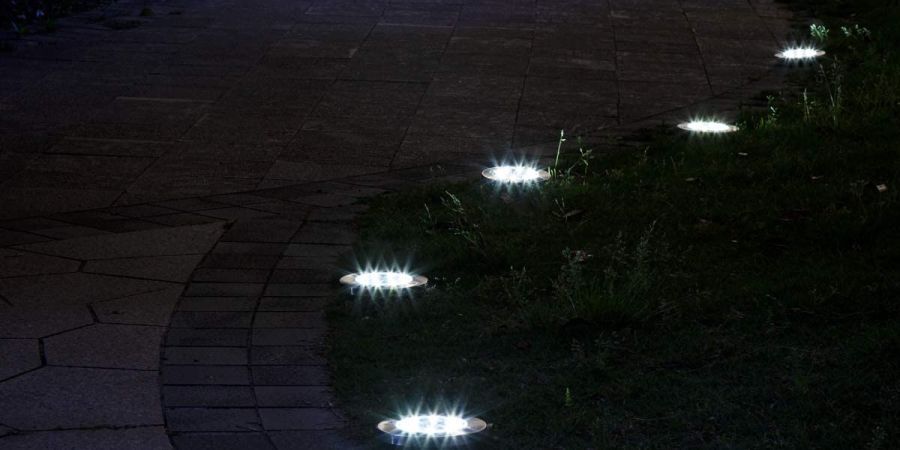 Solar disk lights illuminating a pathway at night.