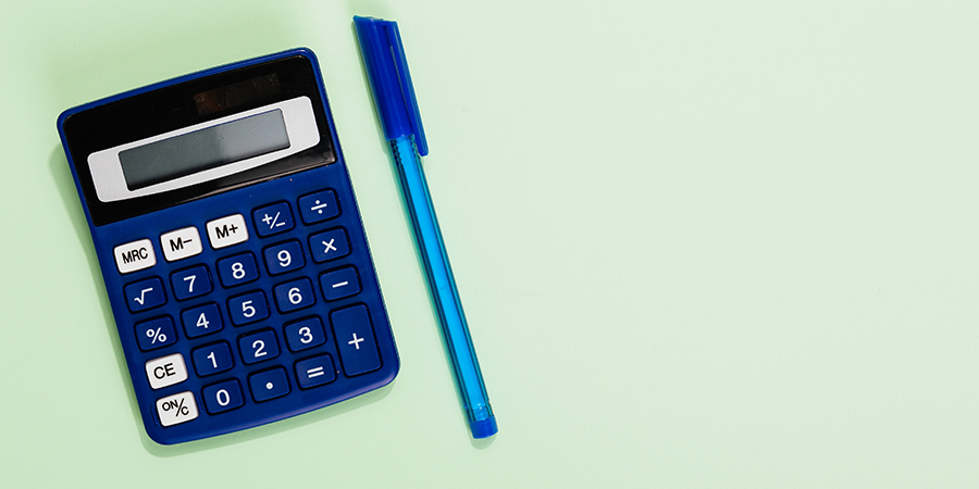 A calculator and a pen on a green background.