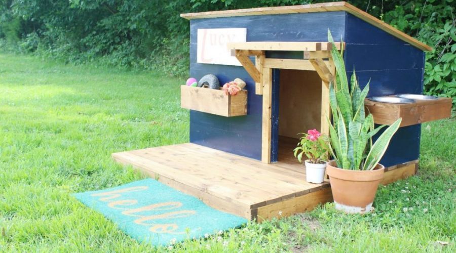 DIY Dog House With Deck sitting on a beautiful lawn.