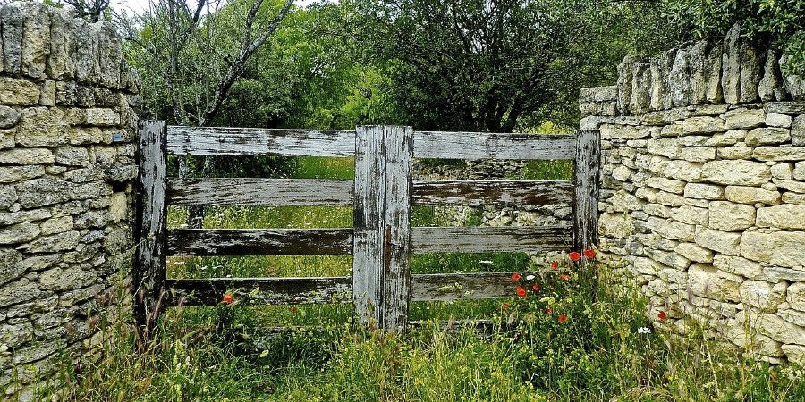 vintage wood gate between stone fence walls
