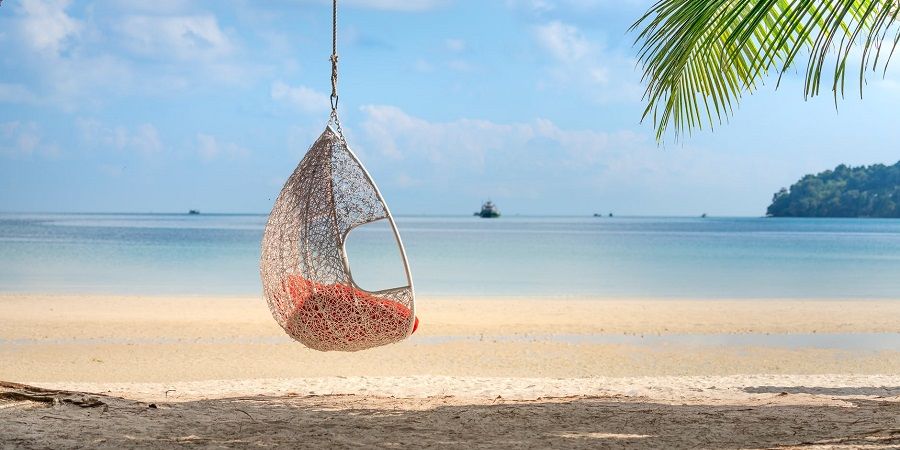 Wicker hanging egg chair on picturesque seaside