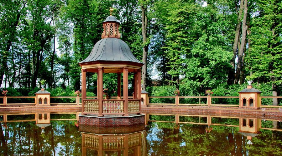 pond with temple-themed wooden gazebo, trees in background