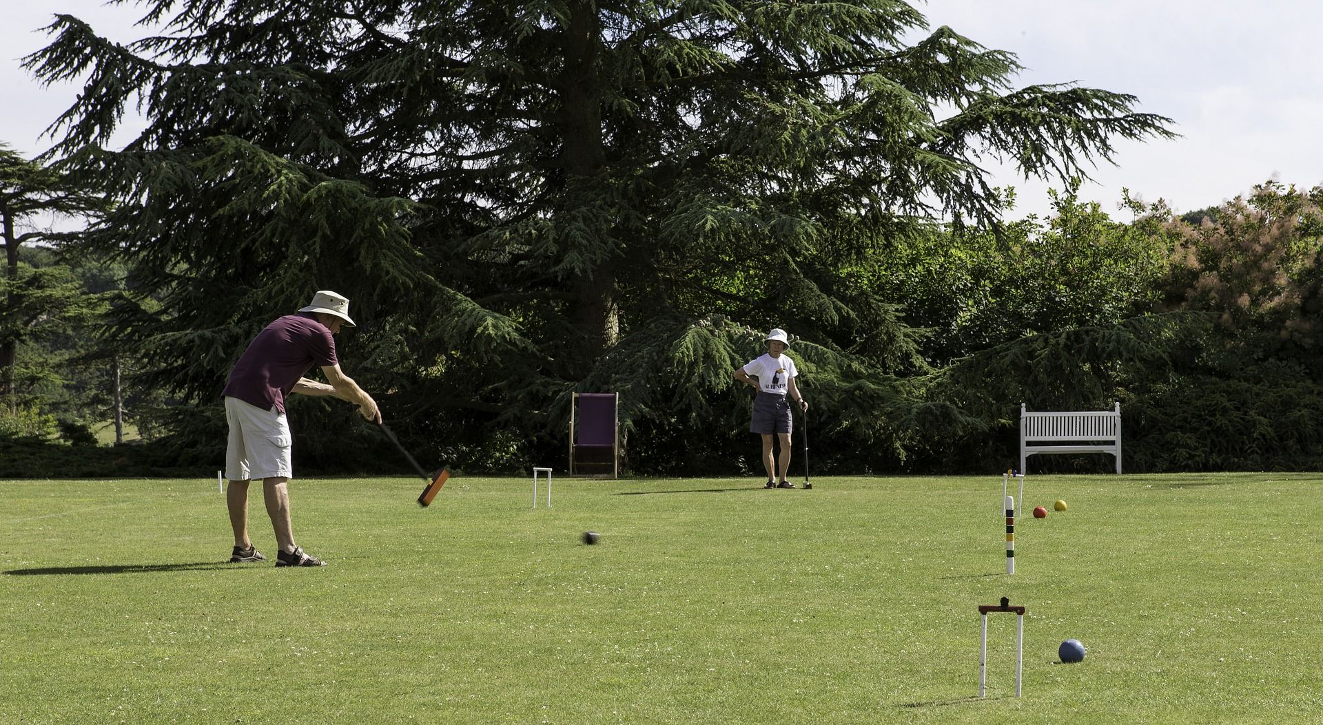 Two people playing Croquet during a sunny day