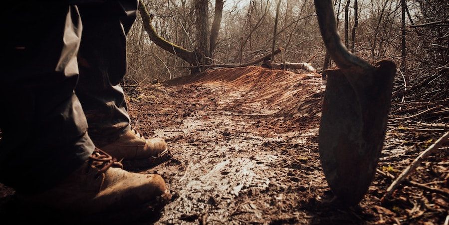 Legs And Shovel On Muddy Path