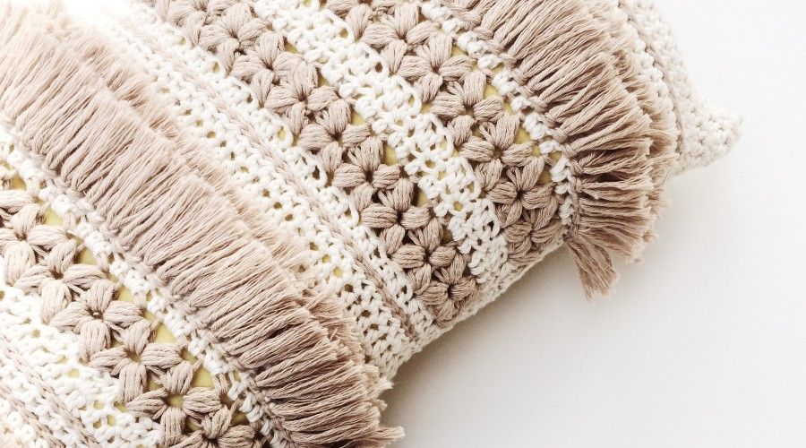 Close view of a white and beige crocheted pillow