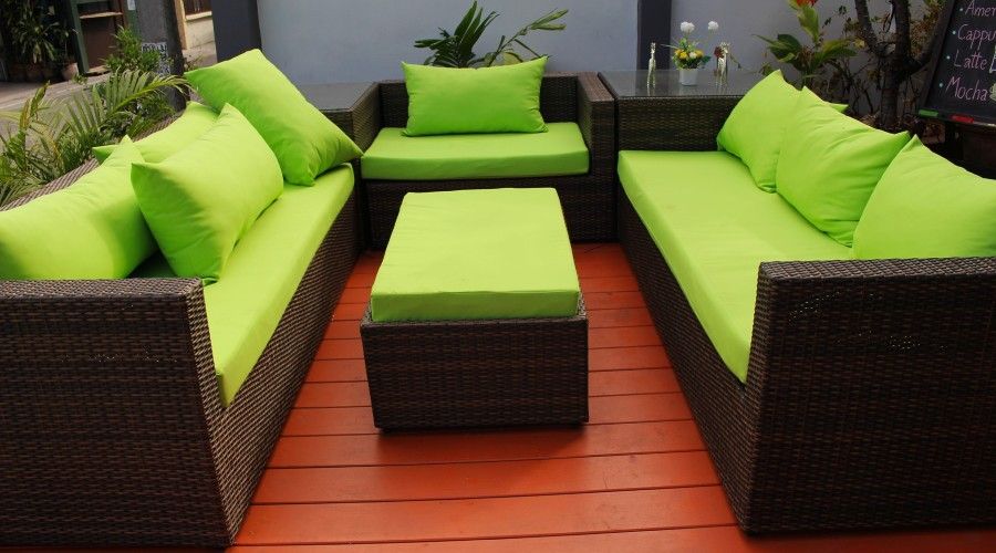 Two dark wicker couches and a chair with matching lime green cushions and throw pillows