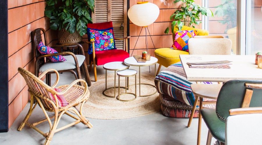 a small outdoor seating area with chairs and throw pillows of different colors and styles