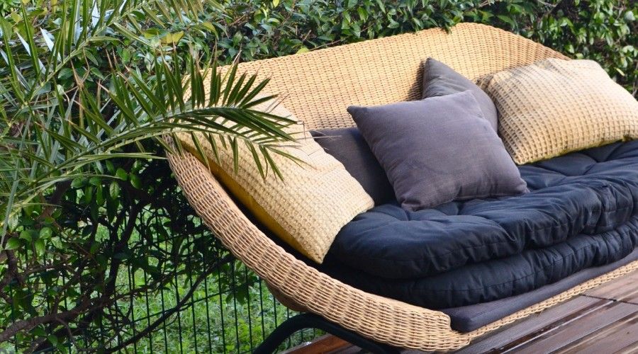 navy blue and tan throw pillows on a light colored wicker love seat