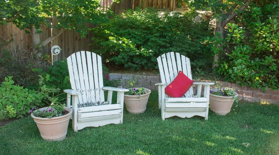 Two Adirondack chairs in a garden