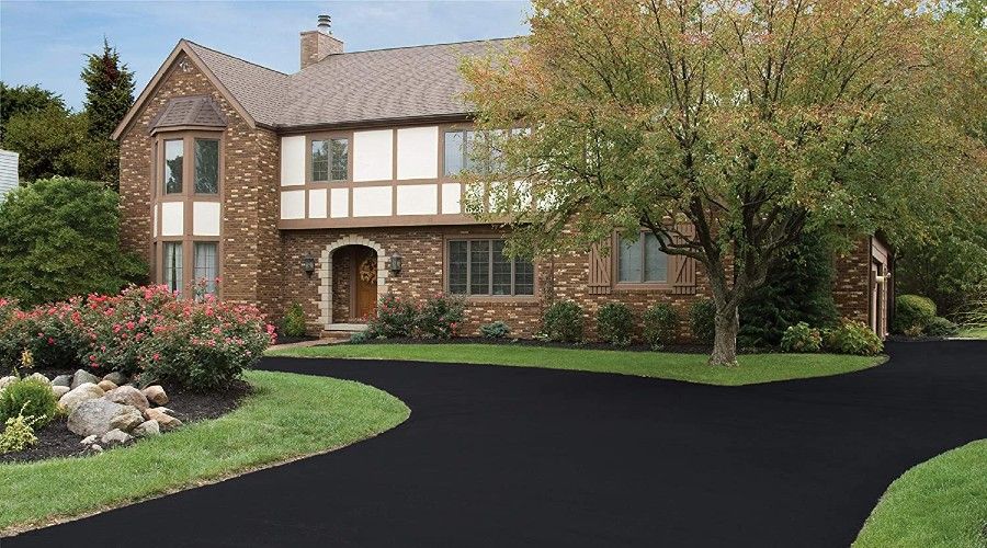 a brick and plaster house with a freshly sealed asphalt driveway