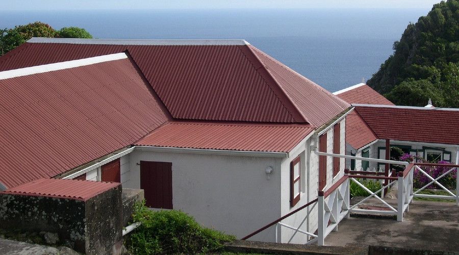 Red metal roof on multi-level house, sea in background