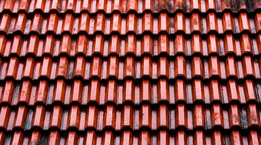 close up of red metal tile roof in rain