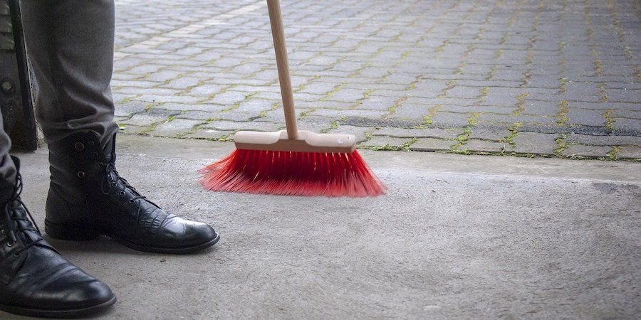 Red broom sweeping driveway 