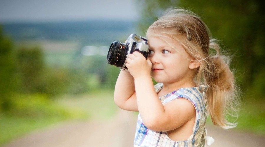 young girl holding camera to her eye