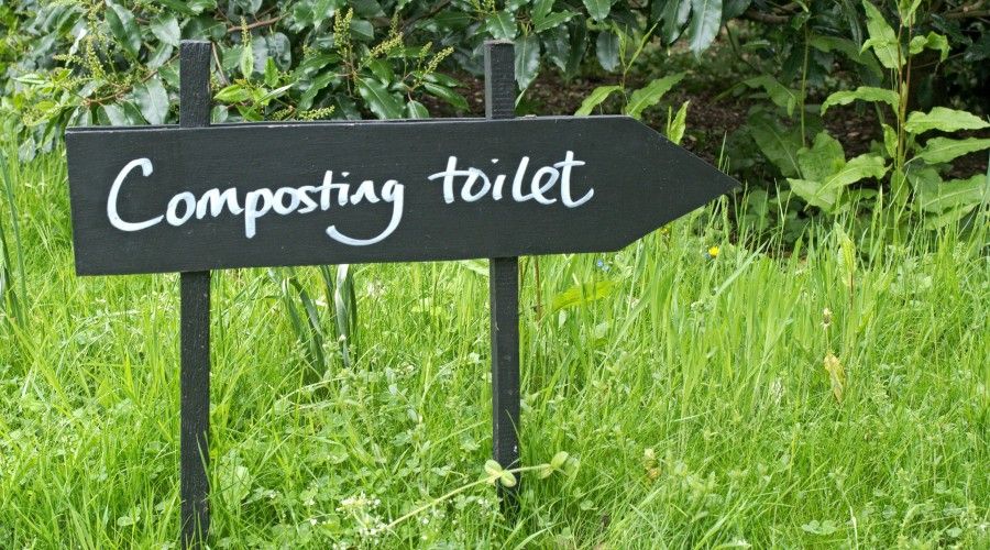 outdoor arrow sign that says Composting Toilet