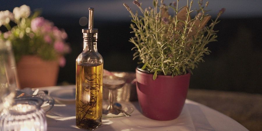 Olive oil on a table with herbs and cutlery 