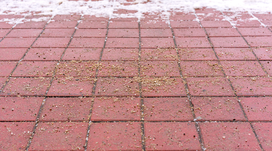 Sand on snowy brick sidewalk