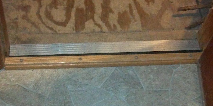 Wooden threshold seal with metal stripping 