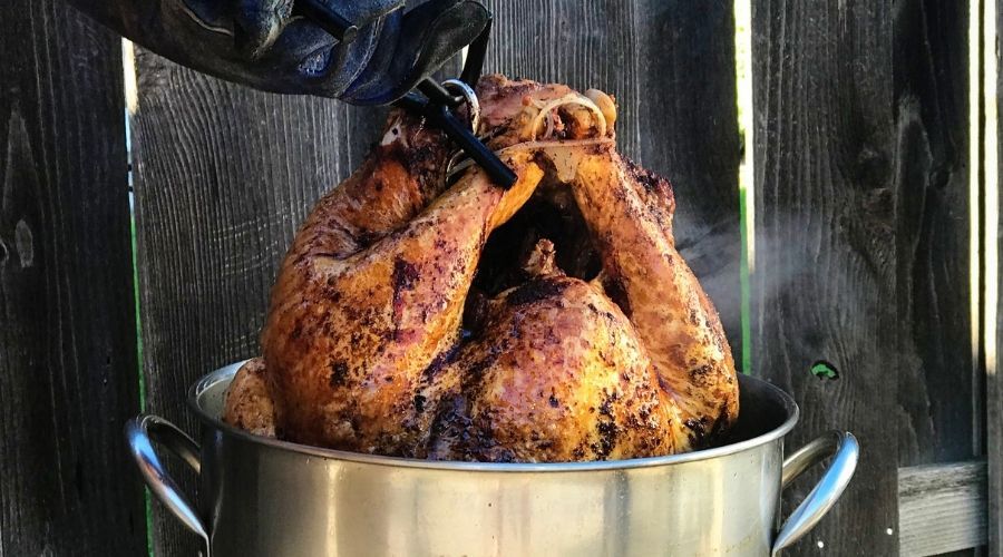 person pulling a finished turkey out of a turkey fryer