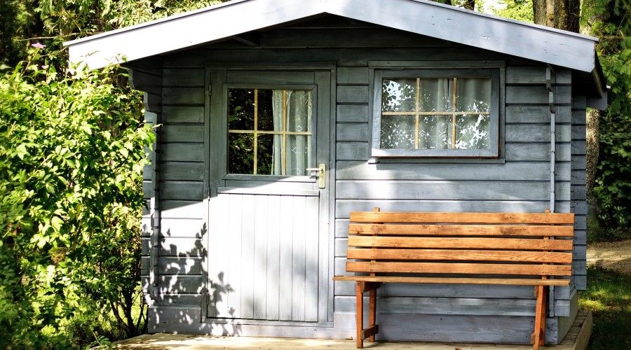 a grey garden shed with a wooden bench