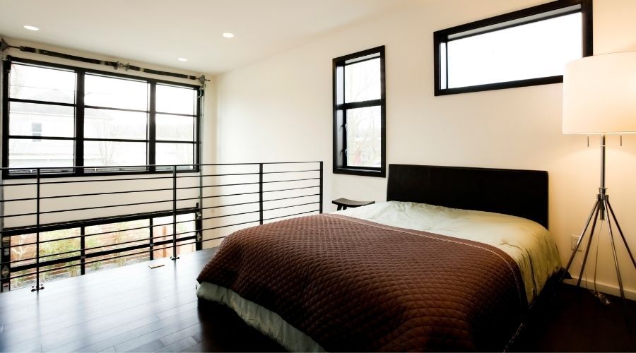 loft bedroom with brown bedding and black iron banisters