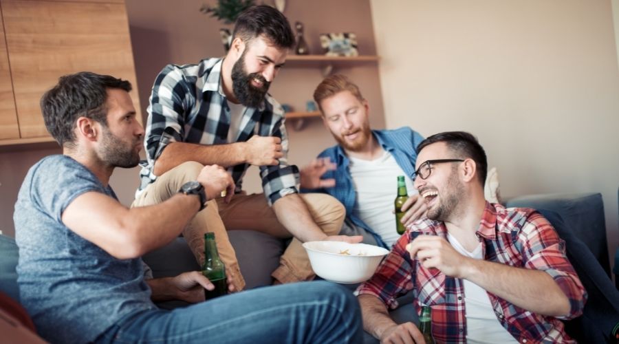 four guys sharing drinks and snacks in a seating space